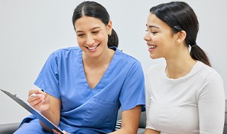 Dental team member talking to female patient about payment options