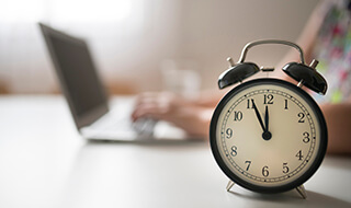 Clock on table next to laptop