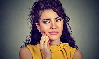 Woman with holding her cheek before emergency dentistry