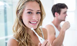 Woman holding toothbrush and smiling in a bathroom