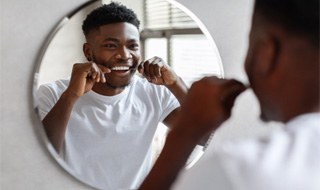 Man smiling at reflection while flossing