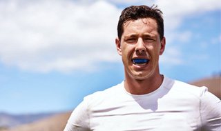 Man in white shirt wearing mouthguard while working out outside