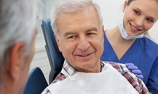Man in dental chair talking to dentist about tooth extractions