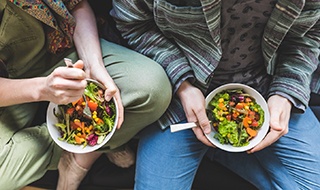 Bird’s eye view of two people holding salads