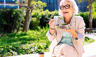 Lady smiles while eating salad