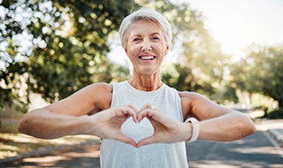 Smiling lady makes shape of heart with her hands