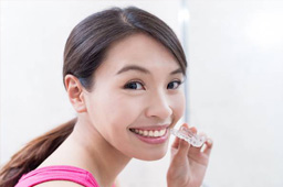 Smiling woman holding Invisalign tray