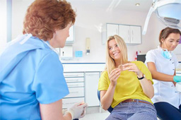 Smiling woman in dental chair holding Invisalign tray