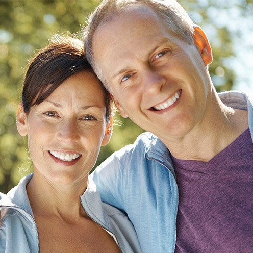 Older couple standing outdoors smiling