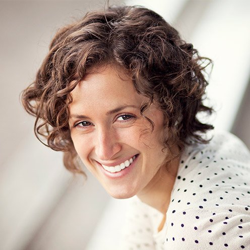 Woman with short curly brown hair smiling