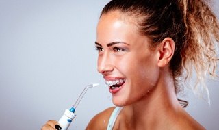 A woman using a water pik to floss her teeth