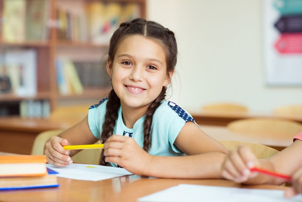 Young girl smiling while sitting in classroom