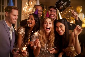 Diverse group of people smiling and celebrating new year's with sparklers and champagne