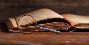 Dusty book opened next to a dusty magnifying glass